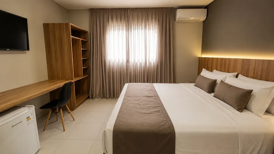 Quarto individual ou casal da Pousada Itaretama com cama ampla, ar-condicionado, mesa de apoio e frigobar